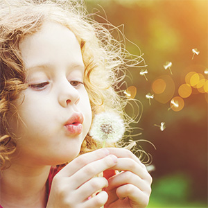 Photo of girl blowing on a dandelion